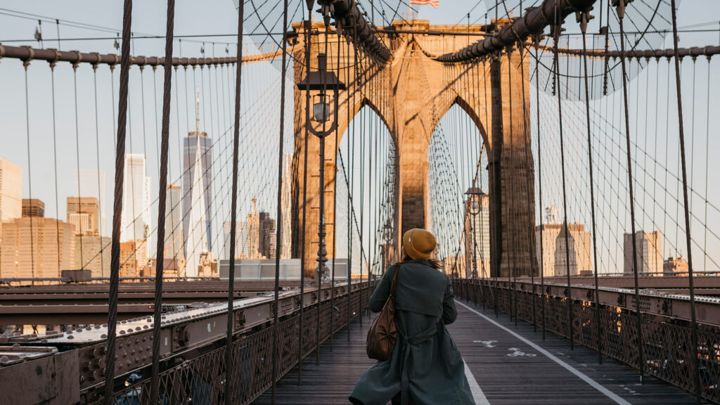 Turista cruza por el puente de Brooklyn. Envato