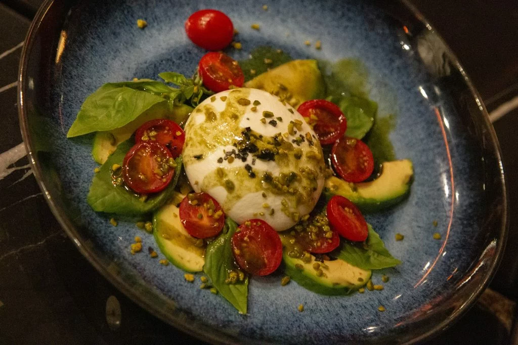 Ensalada de burrata con un abanico de aguacate, frutos secos y tomates cherry sicilianos
