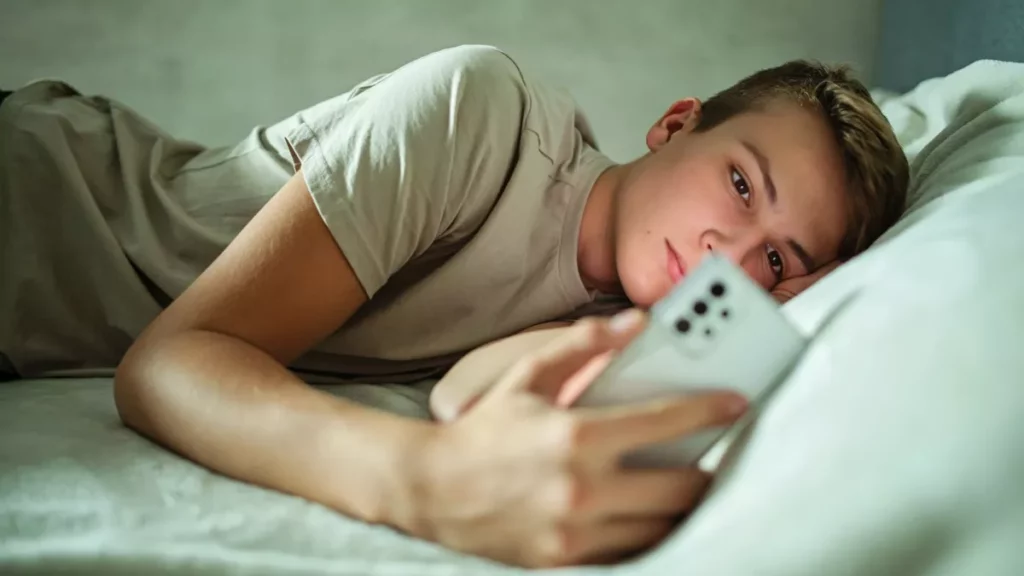 Adolescente mirando su teléfono móvil en la cama