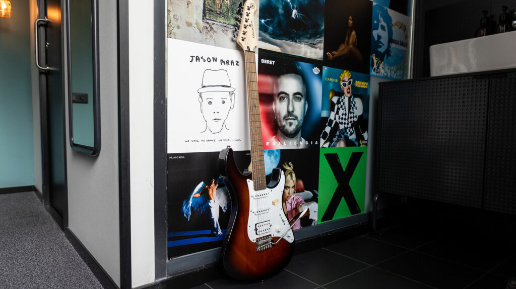 Pared de carátulas y una guitarra eléctrica en el The Social Hub