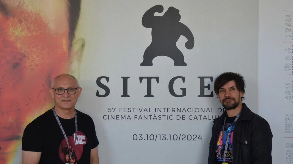 Mario Herrera y Santi Serrano, de Pánico en la sala, frente al cartel de la presente edición del Festival de Sitges.