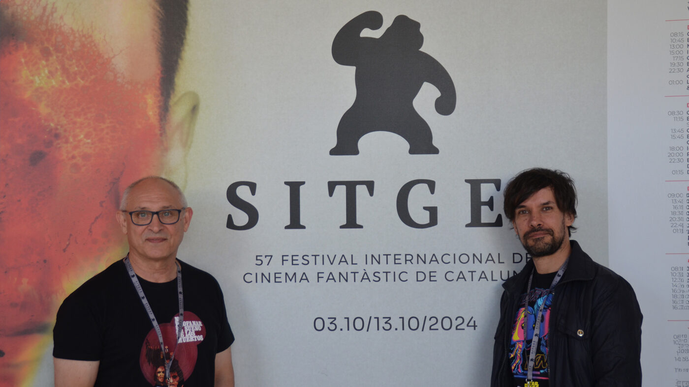 Mario Herrera y Santi Serrano, de Pánico en la sala, frente al cartel de la presente edición del Festival de Sitges.