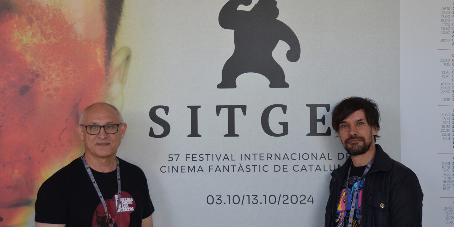 Mario Herrera y Santi Serrano, de Pánico en la sala, frente al cartel de la presente edición del Festival de Sitges.