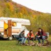 Un grupo de amigos disfrutan del atardecer frente a su autocaravana. Fotografía de Freepik.