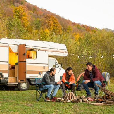 Un grupo de amigos disfrutan del atardecer frente a su autocaravana. Fotografía de Freepik.