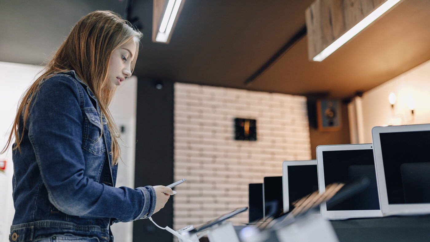 Chica inspeccionando expositor de móviles en el Black Friday