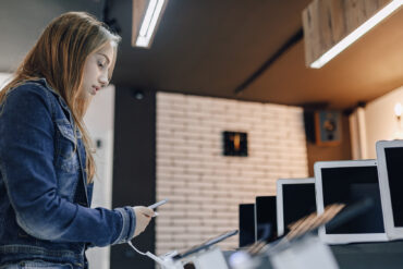 Chica inspeccionando expositor de móviles en el Black Friday