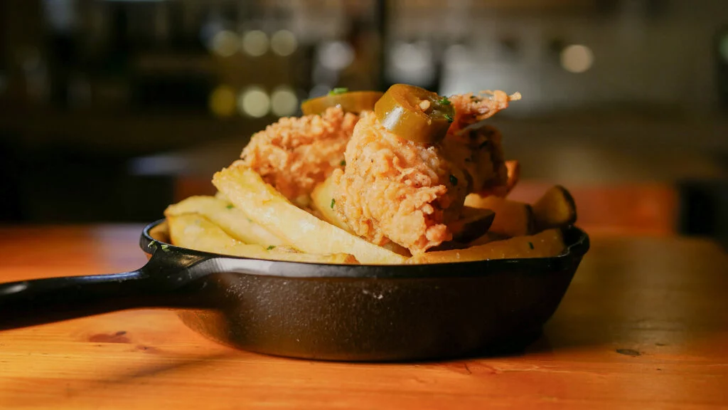 Alitas de pollo crujiente macerado con especias cajún, cebollino y jalapeño con patatas rústicas de Dr. Beer