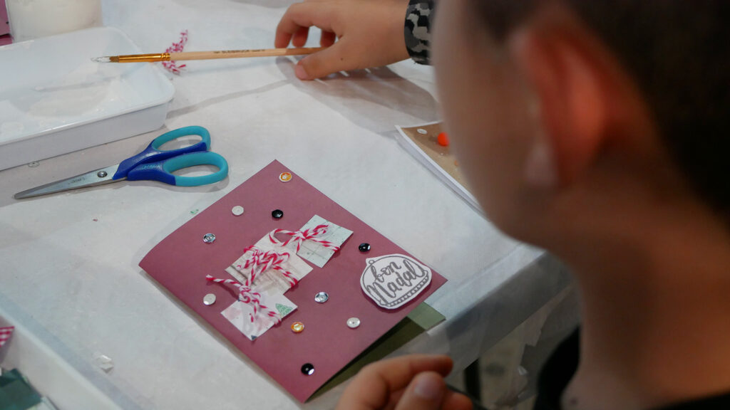 Un joven realizando un taller familiar de decoración de una postal navideña en el Creativa