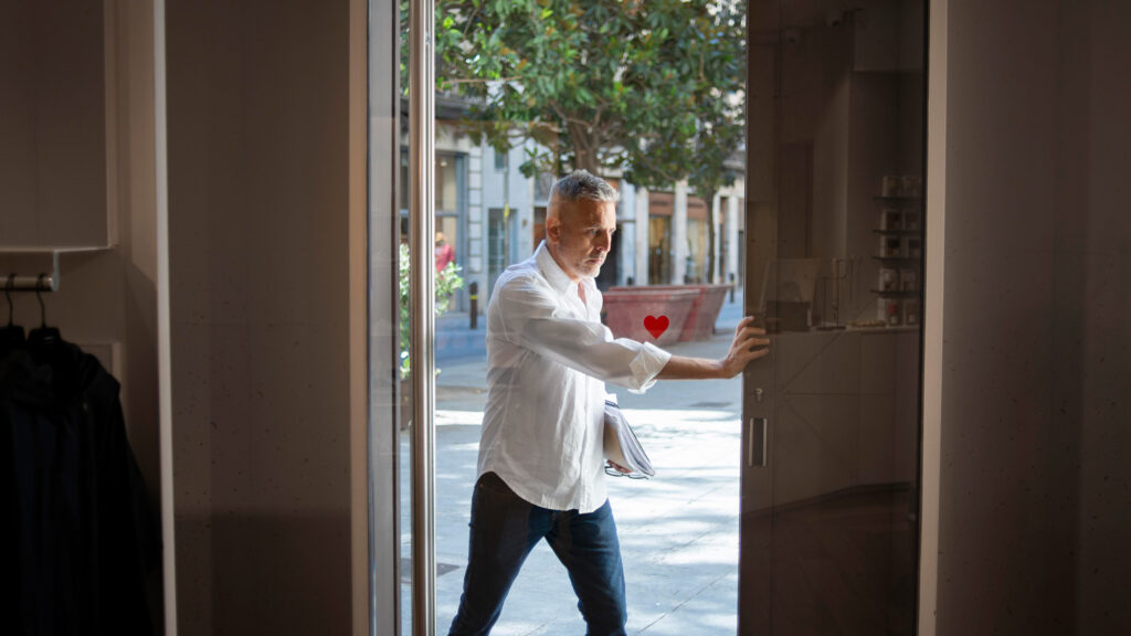 Hombre abriendo la puerta de su negocio. Fotografía de Freepik