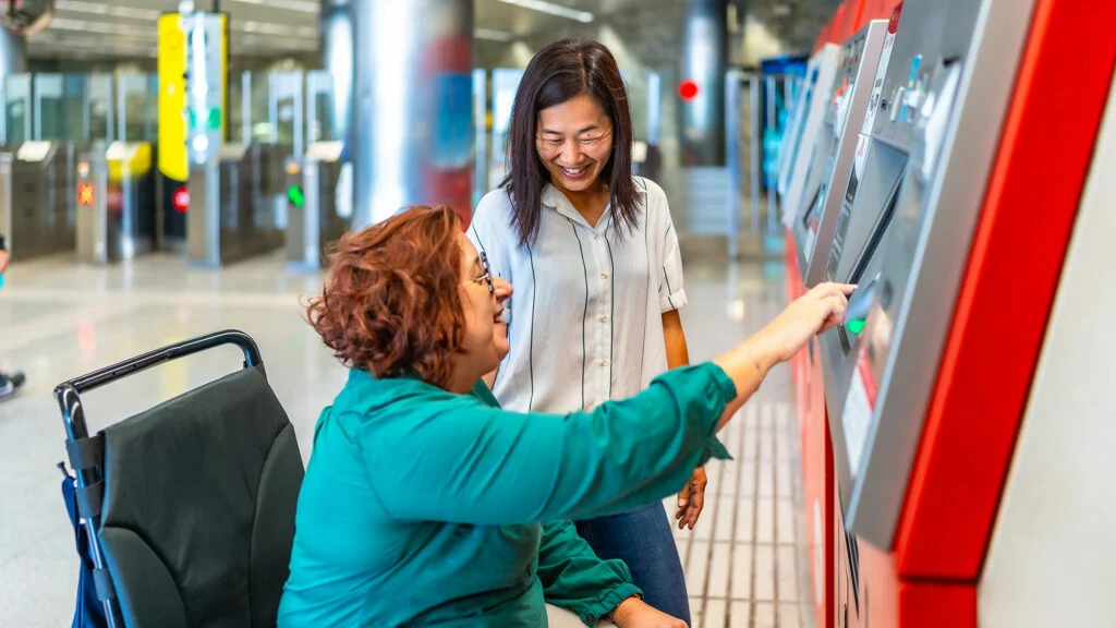 Dos mujeres comprando billetes de transporte público en el metro de Barcelona