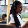 Mujer disfrutando de un podcast en el autobús. Fotografía Envato