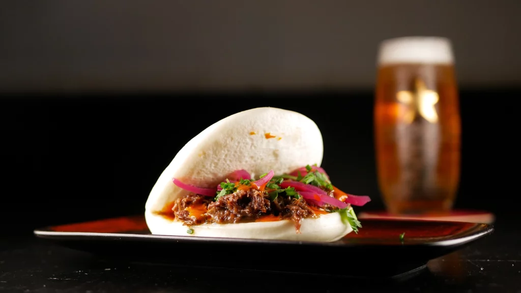 Bao de carrillera desmigada, demi-glace de carne, cebolla roja encurtida, cilantro y salsa casera picante Gochujang del Fat Cat