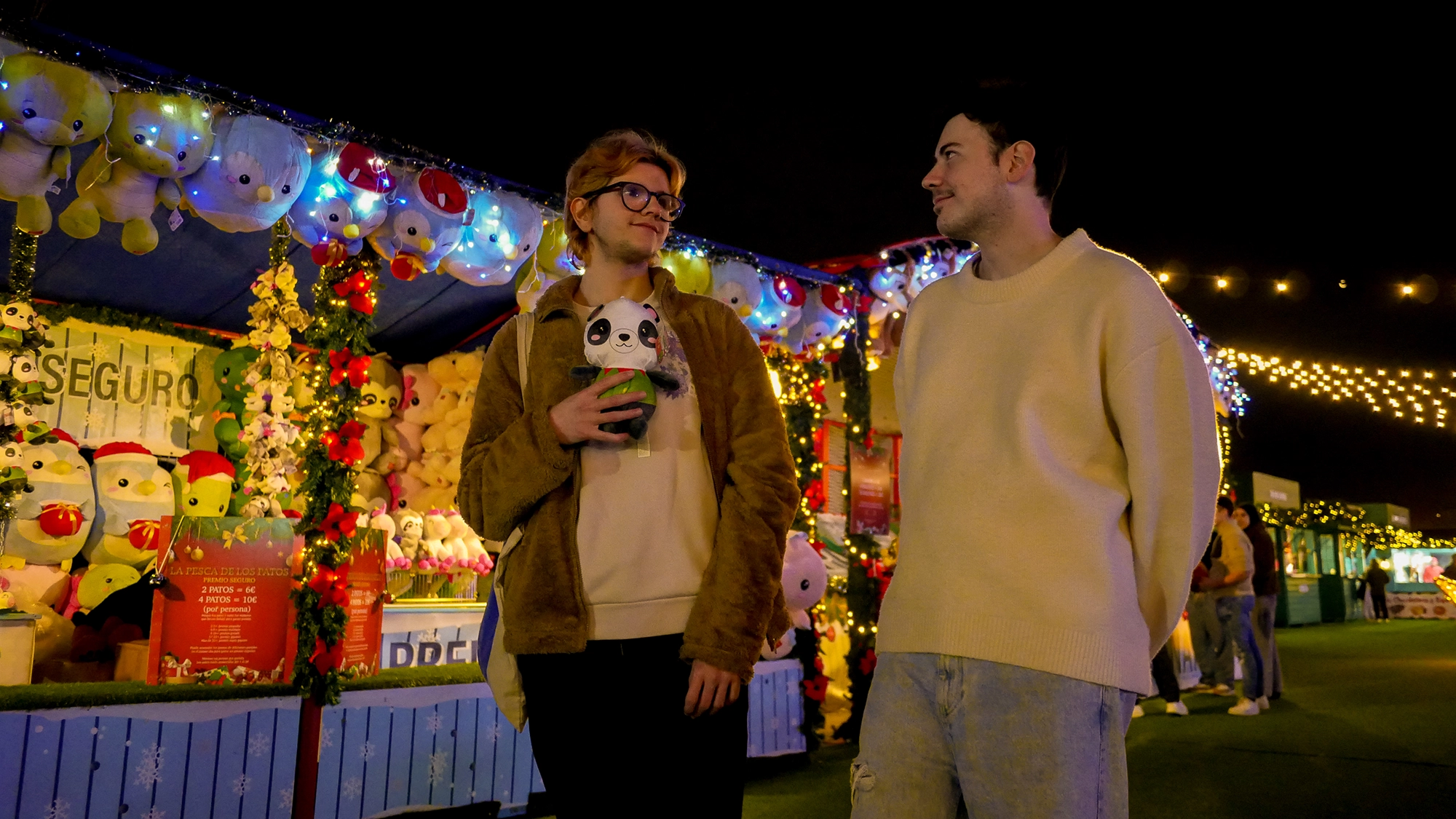 Una pareja de amigos paseando juntos a unos puestos de juegos
