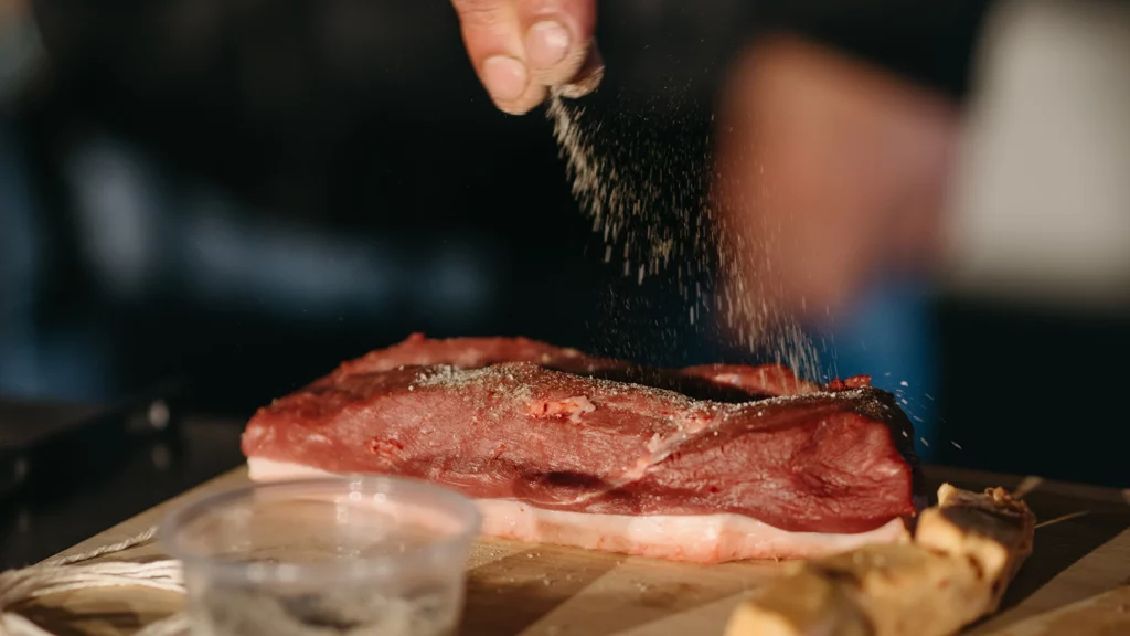 Unas manos especiando una pieza de carne
