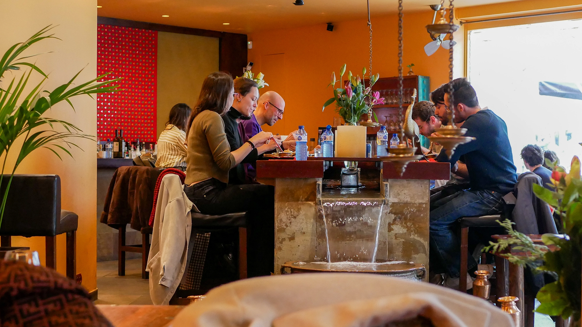Comensales disfrutando de su comida en una original barra alta con cascada de agua