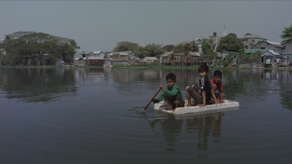 Grupo de niños sobre una plataforma navegado sobre el pueblo inundado tras la tormenta