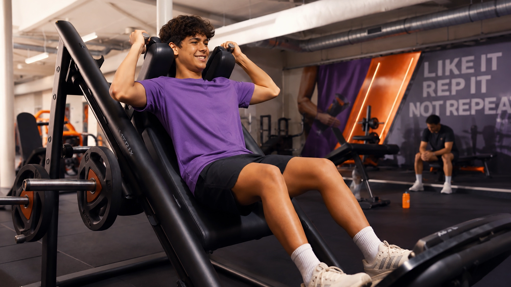 Un joven entrenando peso en una máquina del Basic Fit