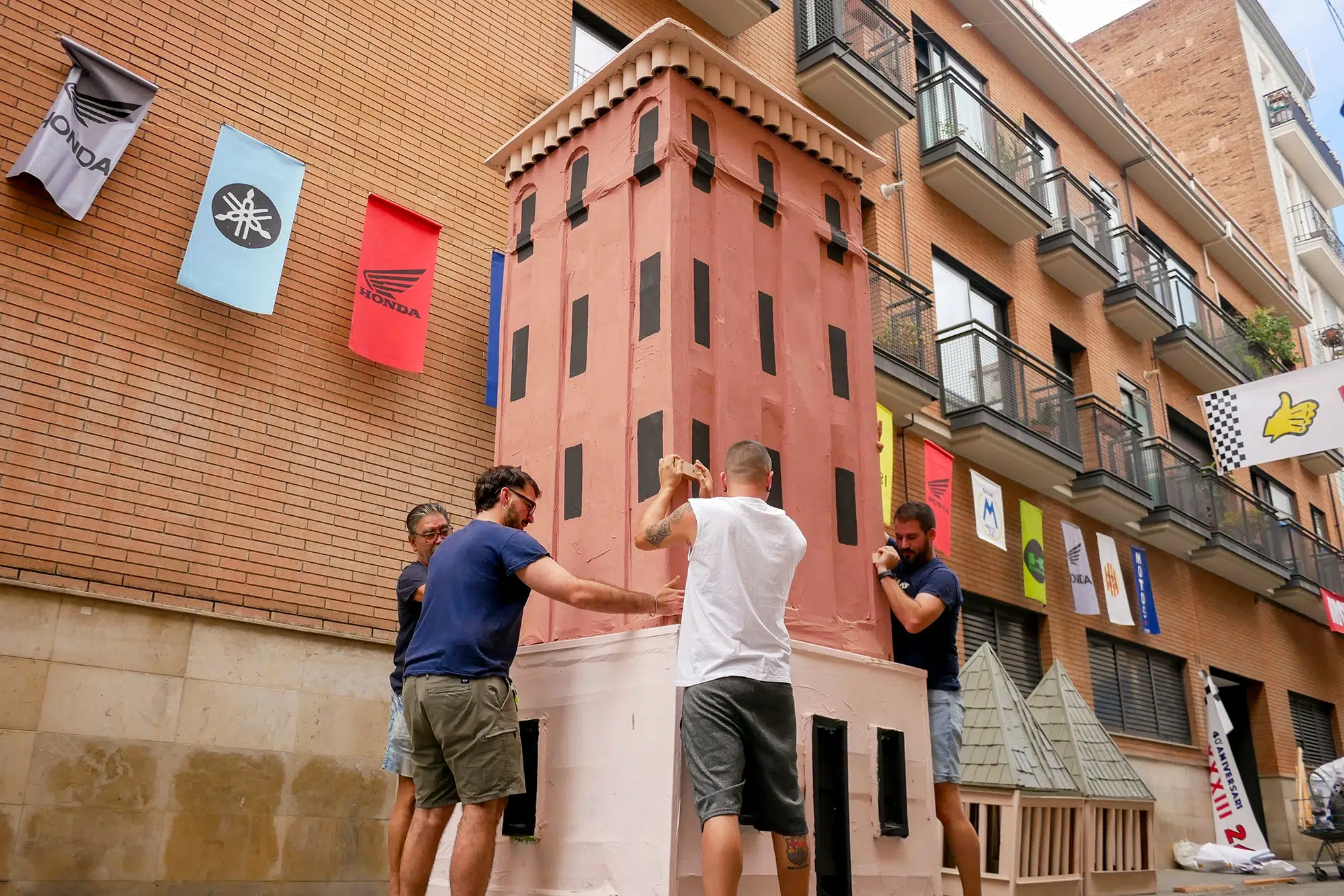 Vecinos de la calle Alcolea de Dalt sosteniendo el cuerpo central de una torre veneciana. Fotografia de Man Hoh Tang