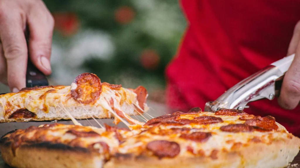 Un cocinero separando una porción de pizza