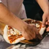 Manos montando una pizza antes de meterla al horno