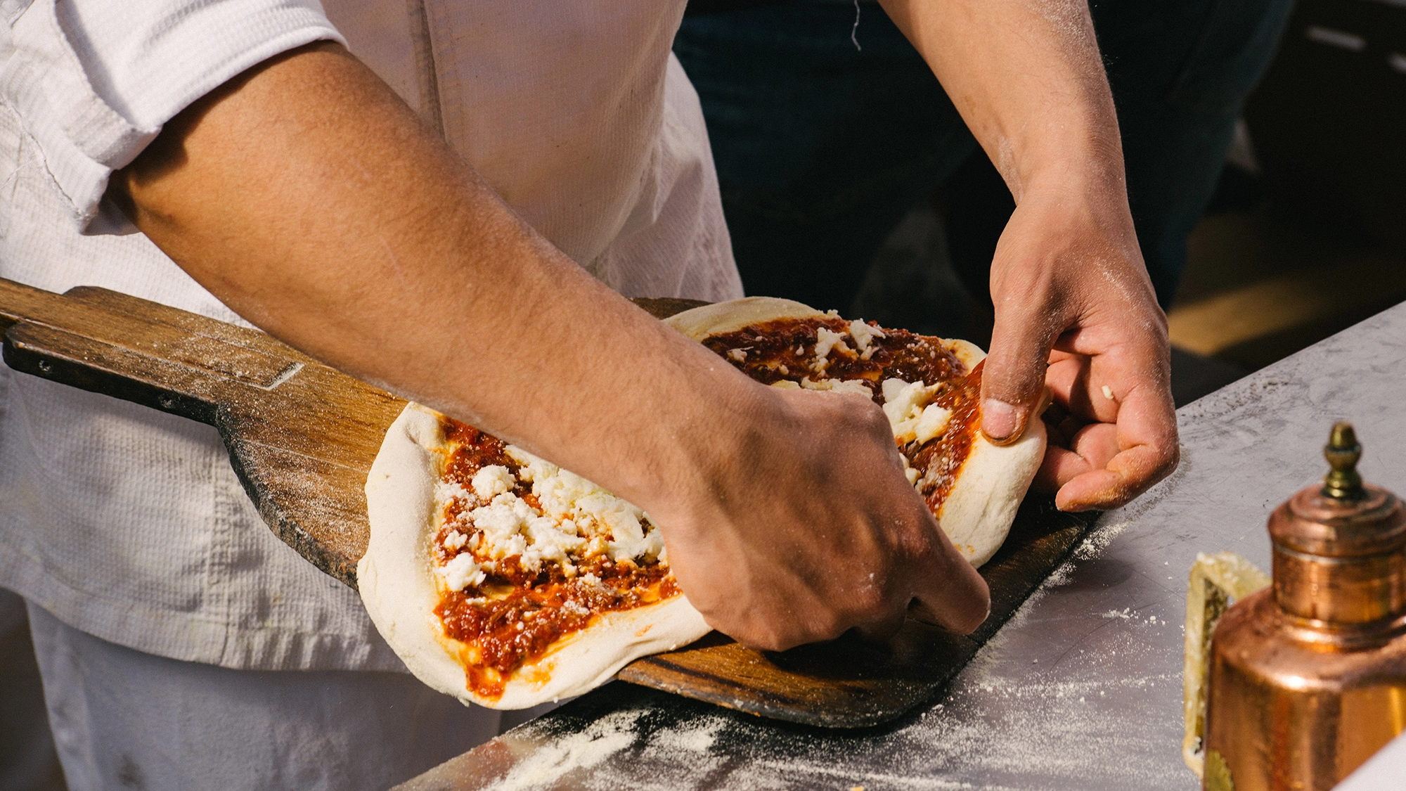 Manos montando una pizza antes de meterla al horno