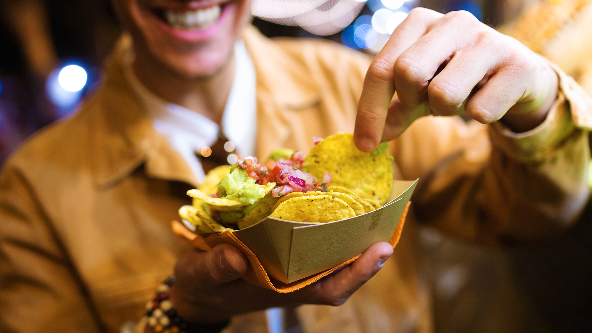 Hombre disfruta de unos nachos en formato street food. Fotografia de Envato