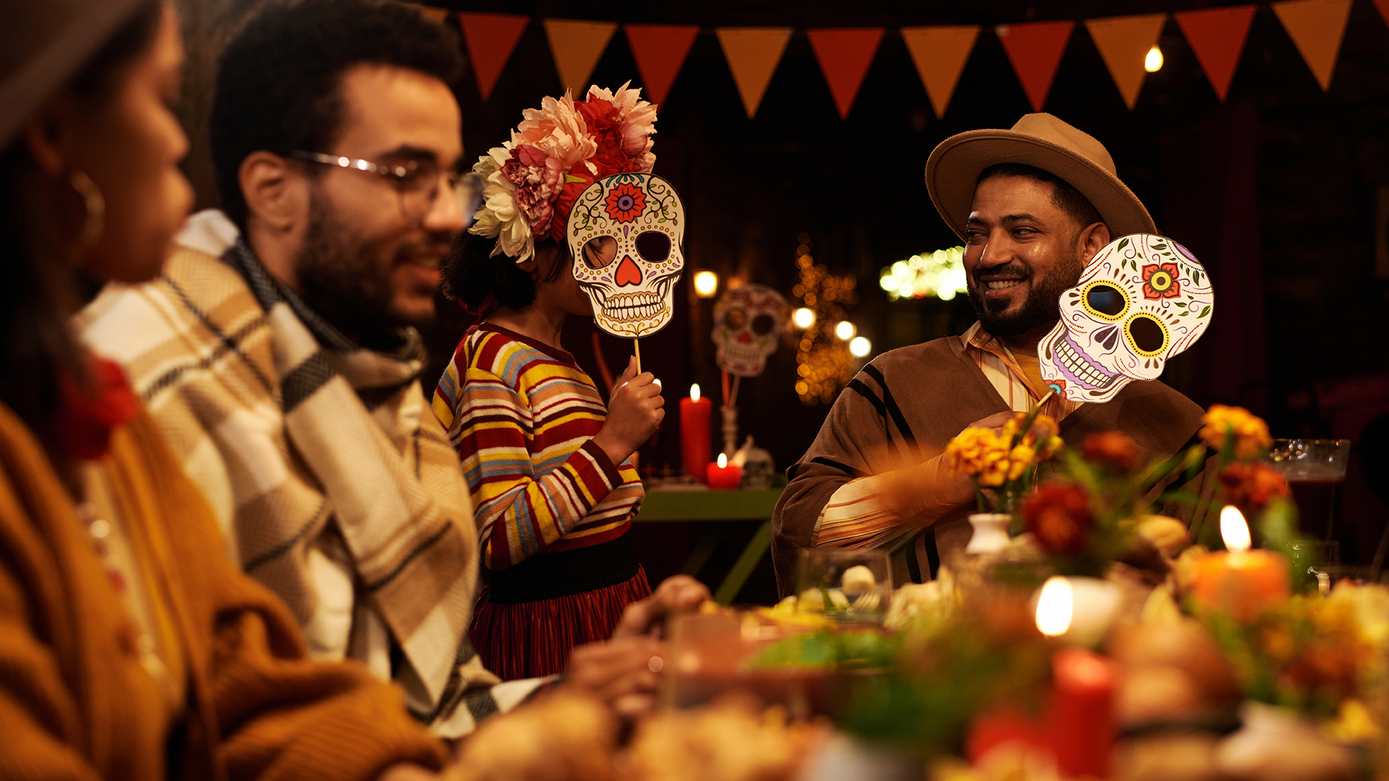 Grupo de personas celebrando el día de los muertos con una rica cena sobre la mesa. Fotografia de Envato
