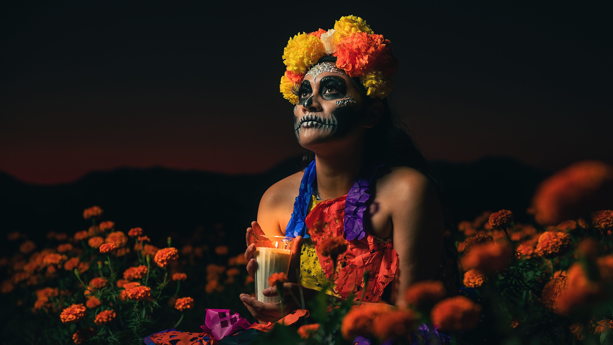Mujer maquillada sujetando una vela en una imagen editorial sobre la ambientación del Día de los Muertos, fotografia de Envato